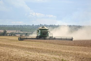 A combine harvester works on a vast soybean field in Paragominas, capturing Brazilian agriculture.